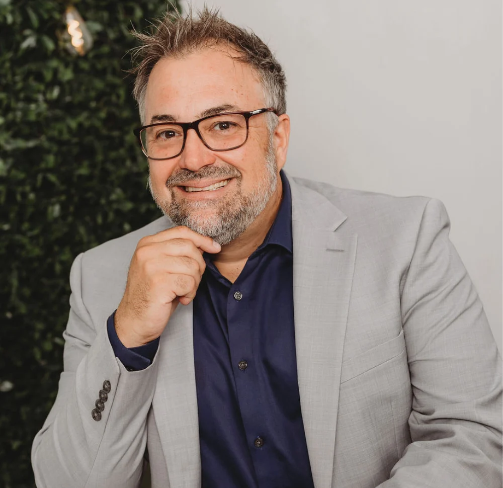 Mario Lambert, conseiller financier, portrait professionnel en veston gris, souriant devant un fond neutre